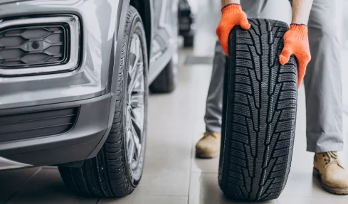 A man holds a tire in a car showroom, demonstrating the process of a tire change.