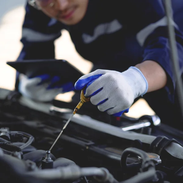 A mechanic in blue gloves and a blue shirt performs maintenance on a car.