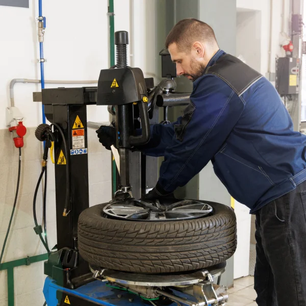 A man in a blue jacket stands next to a tire repair station, ready to assist with vehicle maintenance.