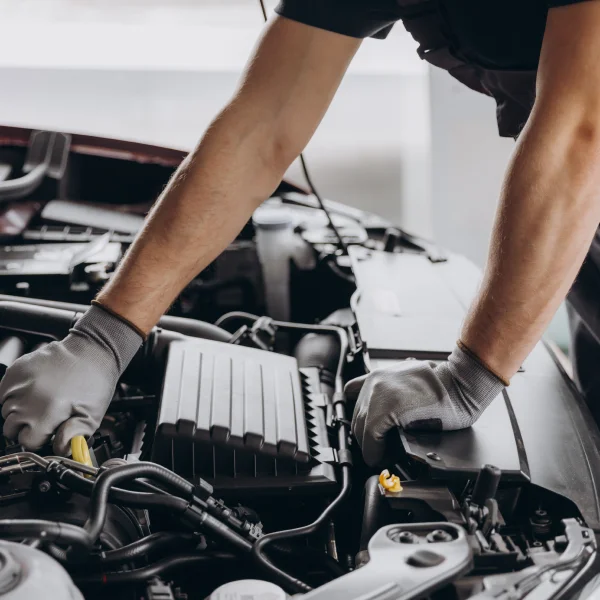 A man performs car diagnostics while working on the engine of a vehicle.