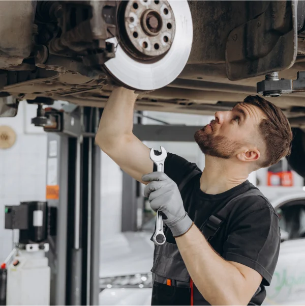 A man performs mechanical verification while working on a car's brake system.