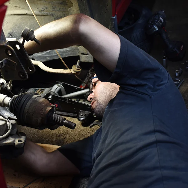 A man performing general mechanics on a car, focused on repairs and maintenance tasks.