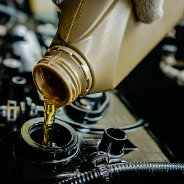 A person pouring oil into a car engine during an oil change, ensuring proper maintenance and performance.