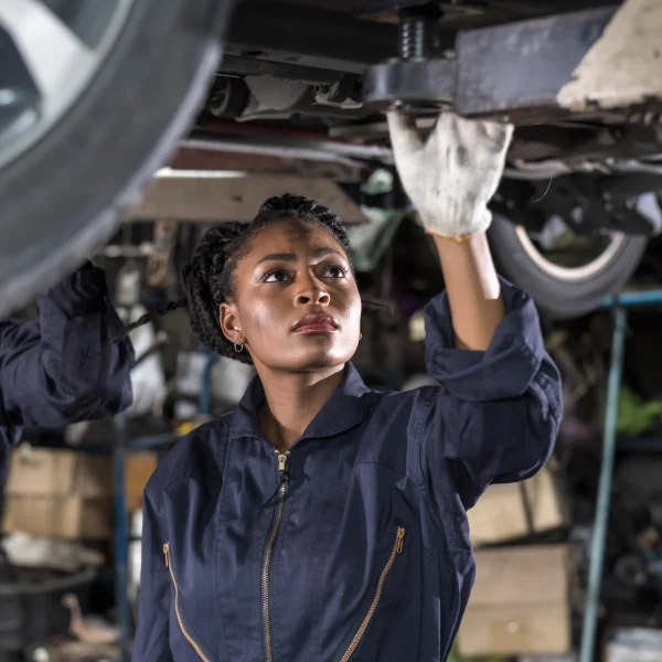 Two women collaborating on auto repair in a garage, demonstrating skill and teamwork in vehicle maintenance.