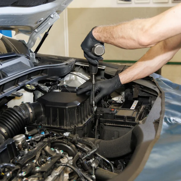 A man performing maintenance on a car in a general mechanics workshop.