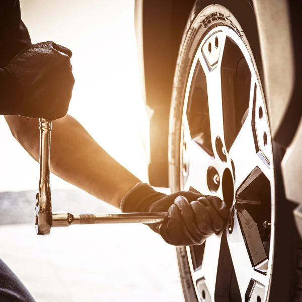 A man is replacing a flat tire on a car, demonstrating essential tire change skills and vehicle maintenance.