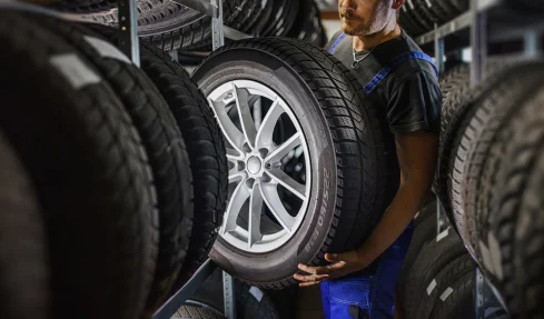 A man holds a tire in a store, showcasing options for customers looking to buy tires.