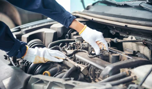 A mobile mechanic in white gloves repairs a car engine, demonstrating expertise and attention to detail.